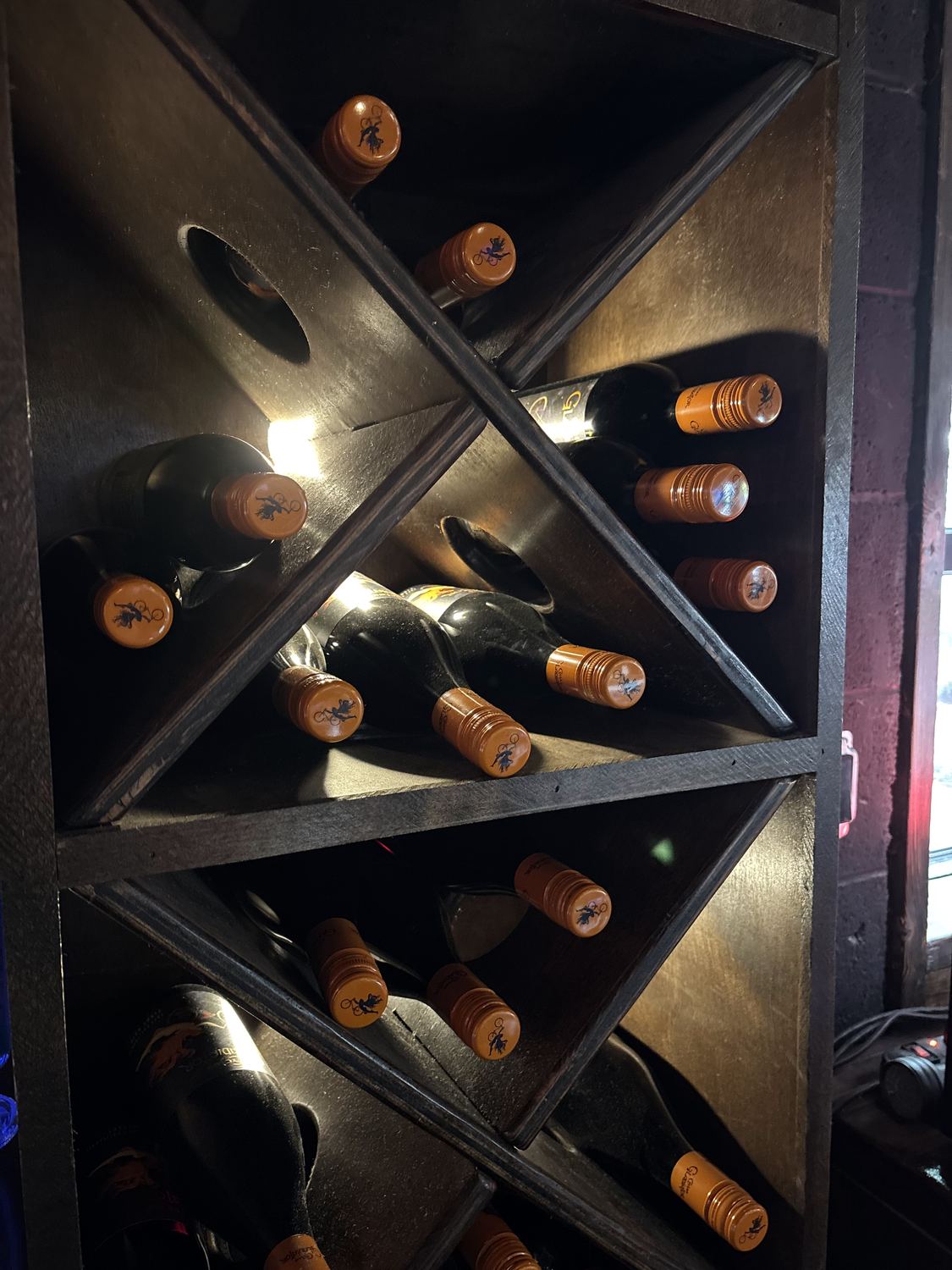 Bottles resting in the dark wooden wine racks